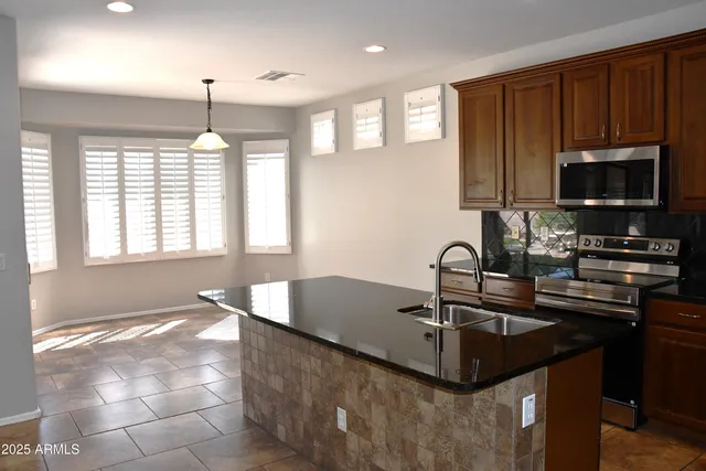 a kitchen with kitchen island granite countertop a sink and a stove top oven with wooden cabinets