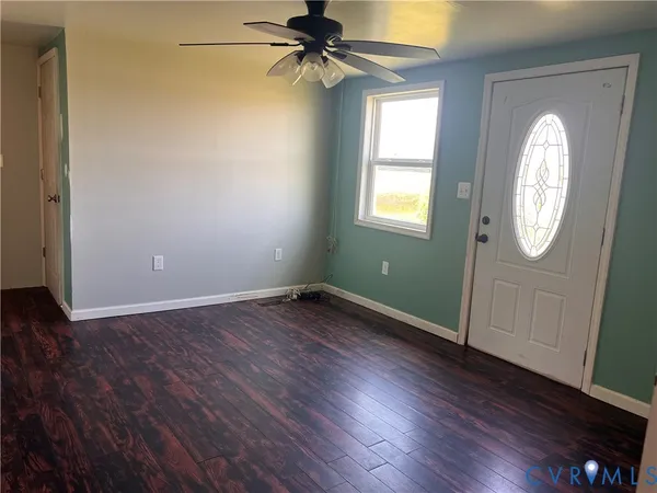 an empty room with wooden floor fan and windows