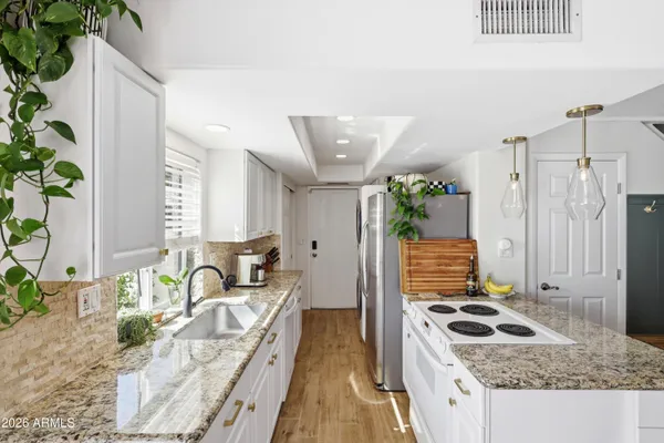 a kitchen with granite countertop a sink stove and refrigerator