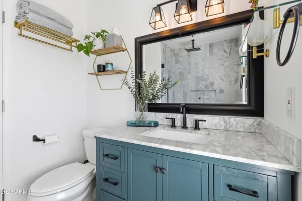 a bathroom with a granite countertop sink mirror vanity and toilet