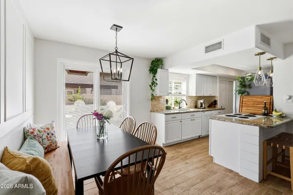 a kitchen with stainless steel appliances granite countertop a stove top oven a refrigerator a sink dishwasher a dining table and chairs with wooden floor