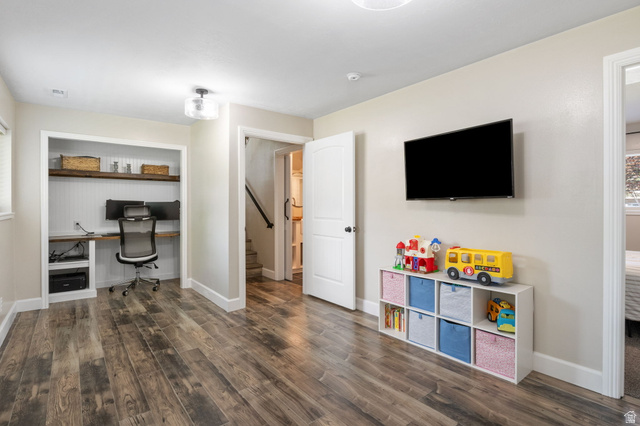 415 360 East Salem, UT 84653 - Photo 13 of 20 Spacious room featuring wood-finish flooring, a built-in desk with shelving, a wall-mounted television, and modern flush-mount lighting