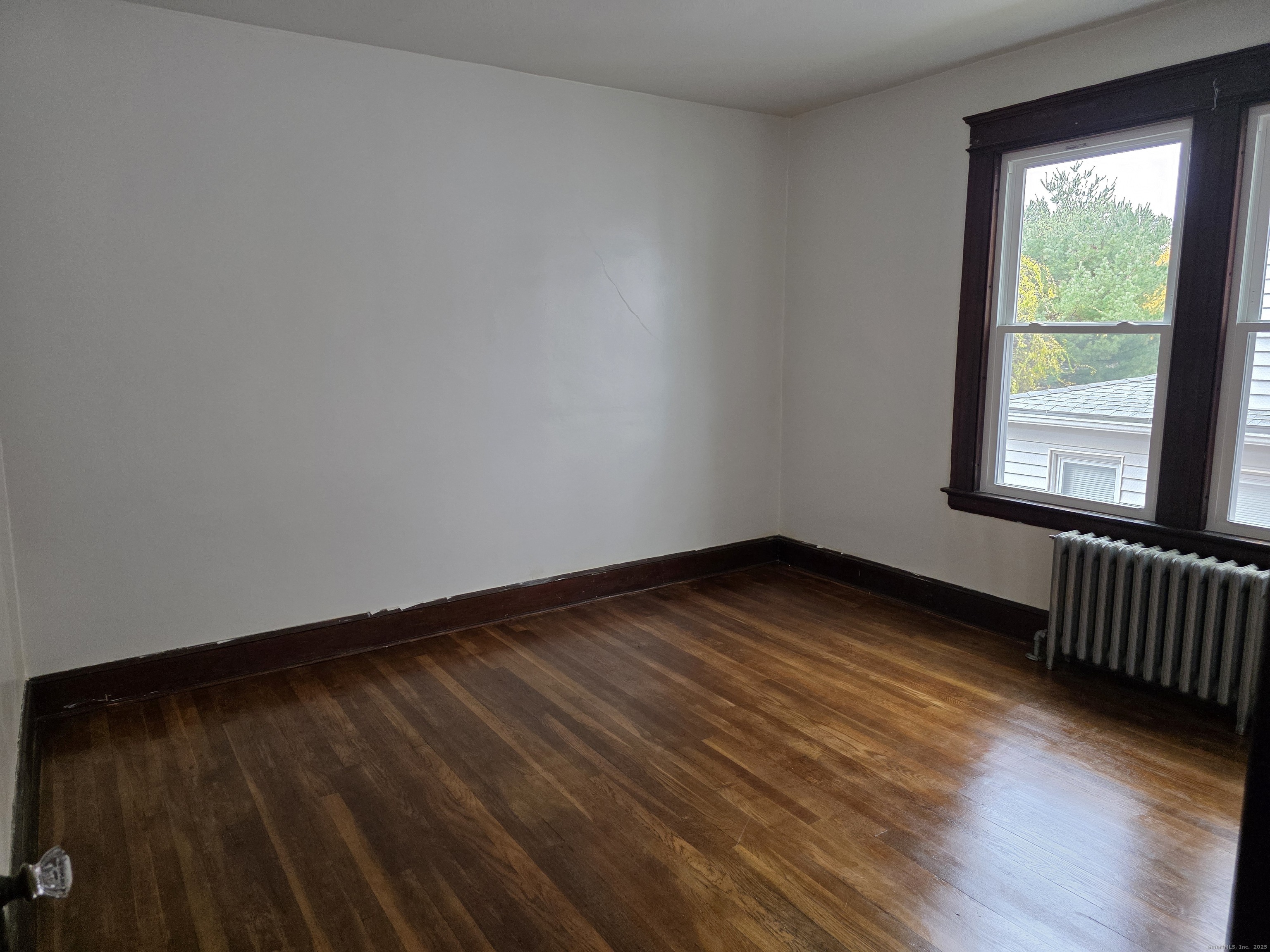 166 Oak Street, Unit 2 Waterbury, CT 06704 - Photo 5 of 13 a view of an empty room with wooden floor and a window