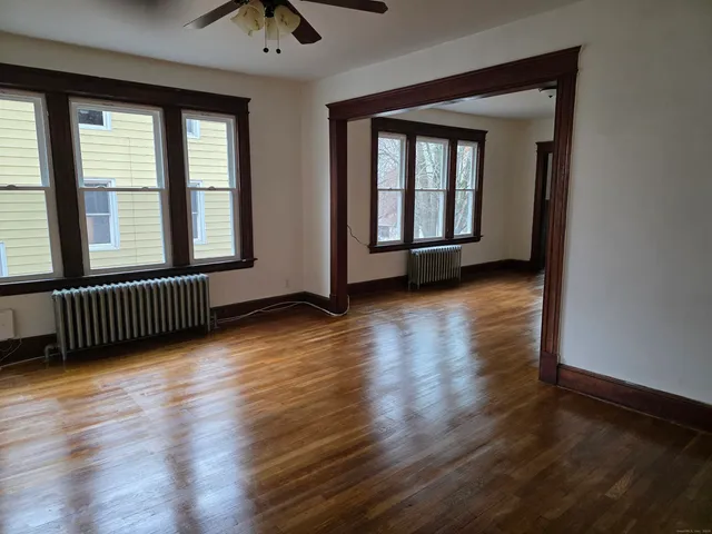 a view of an empty room with wooden floor and a window