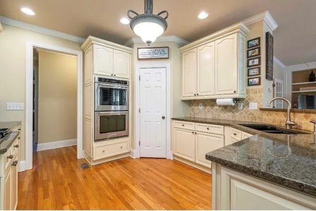 a kitchen with stainless steel appliances granite countertop a sink and dishwasher a refrigerator with wooden floor