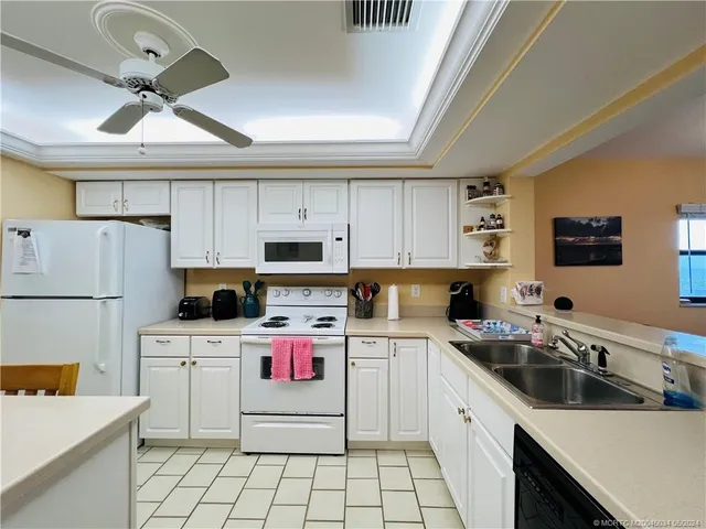 a kitchen with a sink a stove cabinets and white appliances