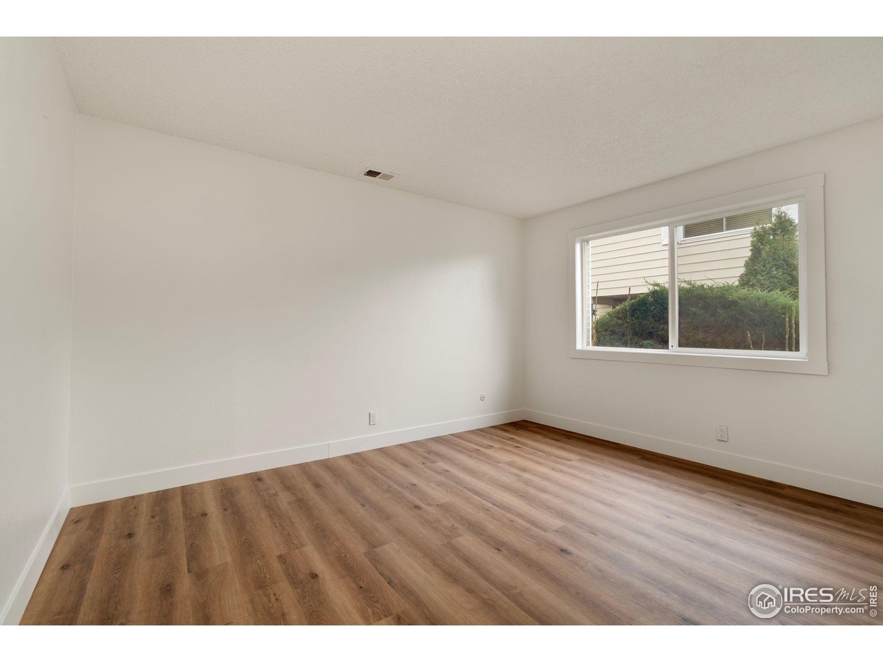 9842 Lane Street Thornton, CO 80260 - Photo 11 of 20 a view of an empty room with wooden floor and windows