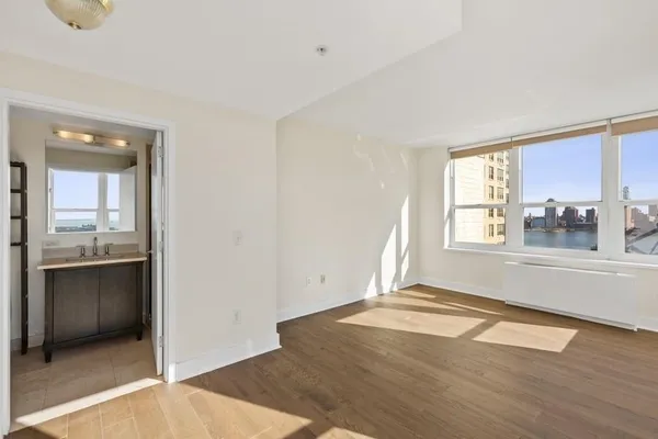 a view of an empty room with wooden floor and a window