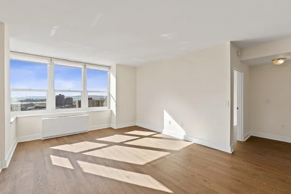 a view of an empty room with window and wooden floor