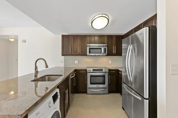 a kitchen with stainless steel appliances granite countertop a sink refrigerator and microwave