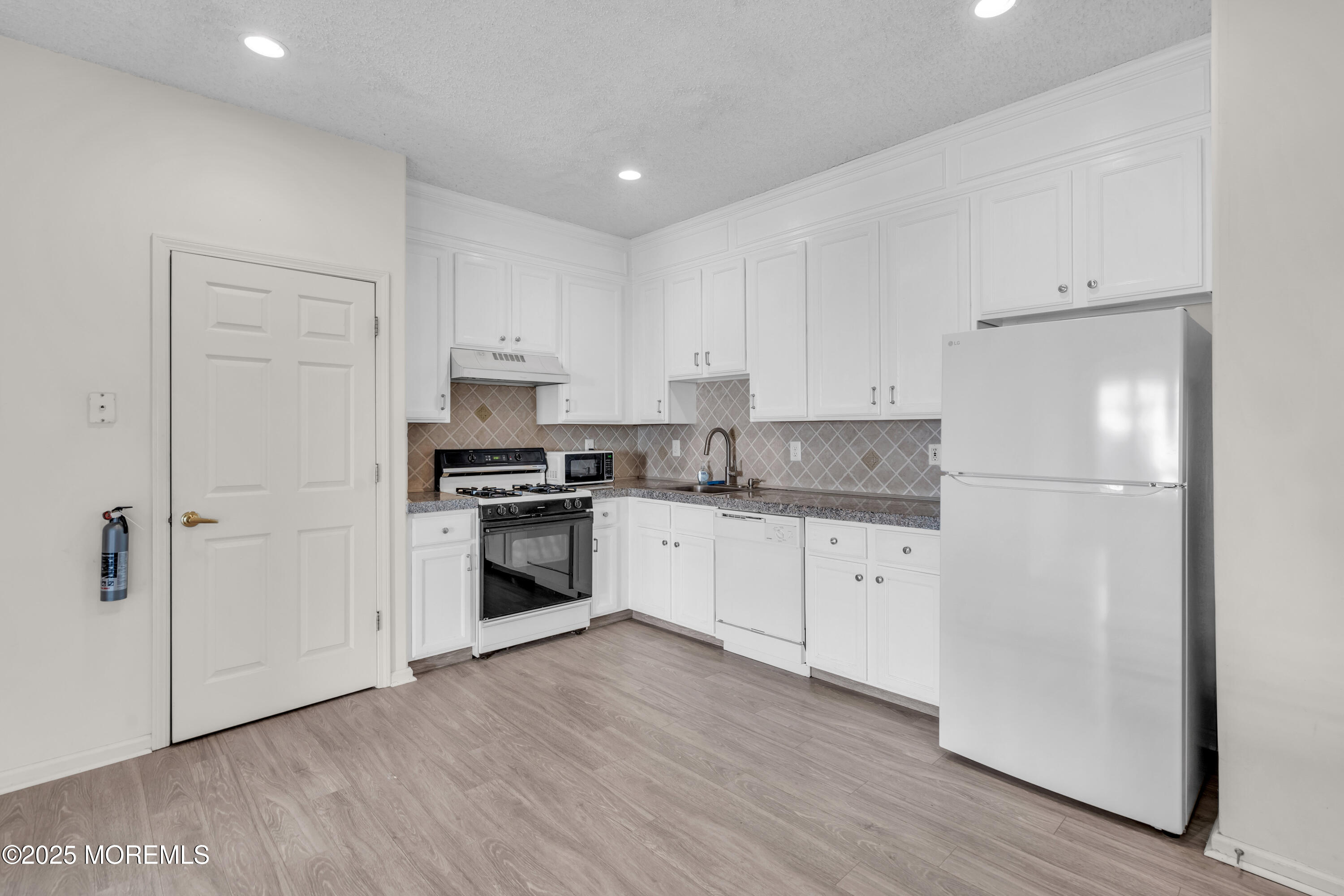 32 Riva Boulevard, Unit 2277 Brick, NJ 08723 - Photo 9 of 23 a kitchen with granite countertop white cabinets and stainless steel appliances