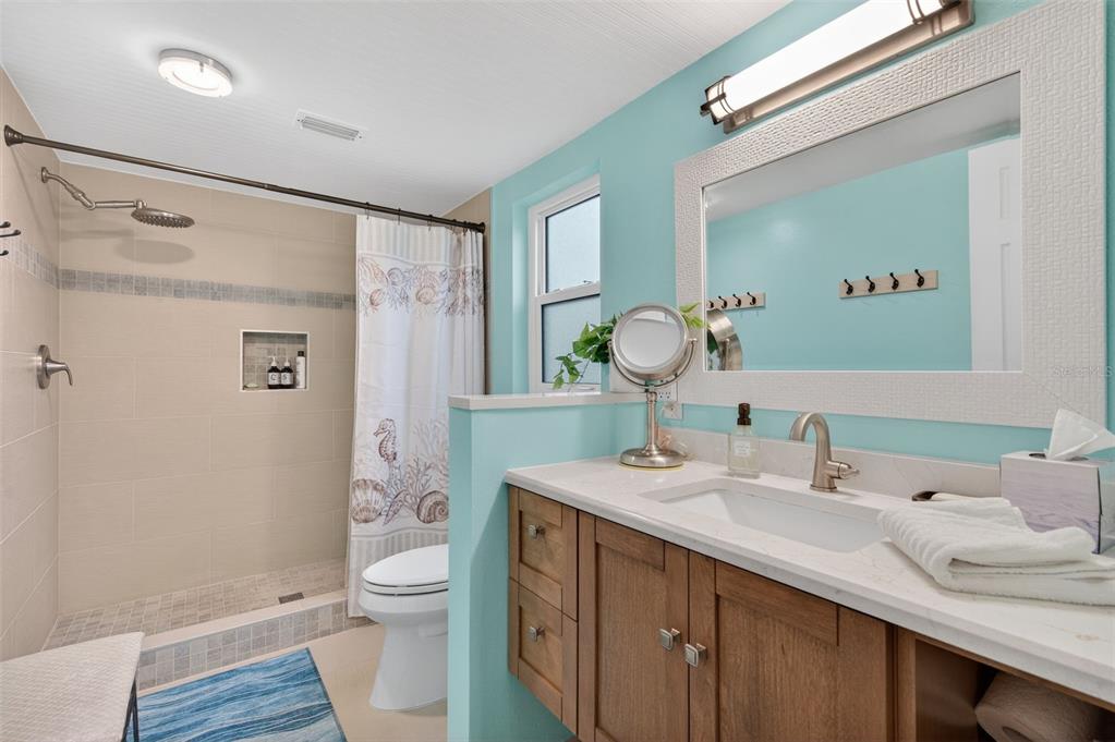 1430 Heather Ridge Boulevard, Unit 101 Dunedin, FL 34698 - Photo 30 of 44 a bathroom with a granite countertop sink a toilet and a mirror