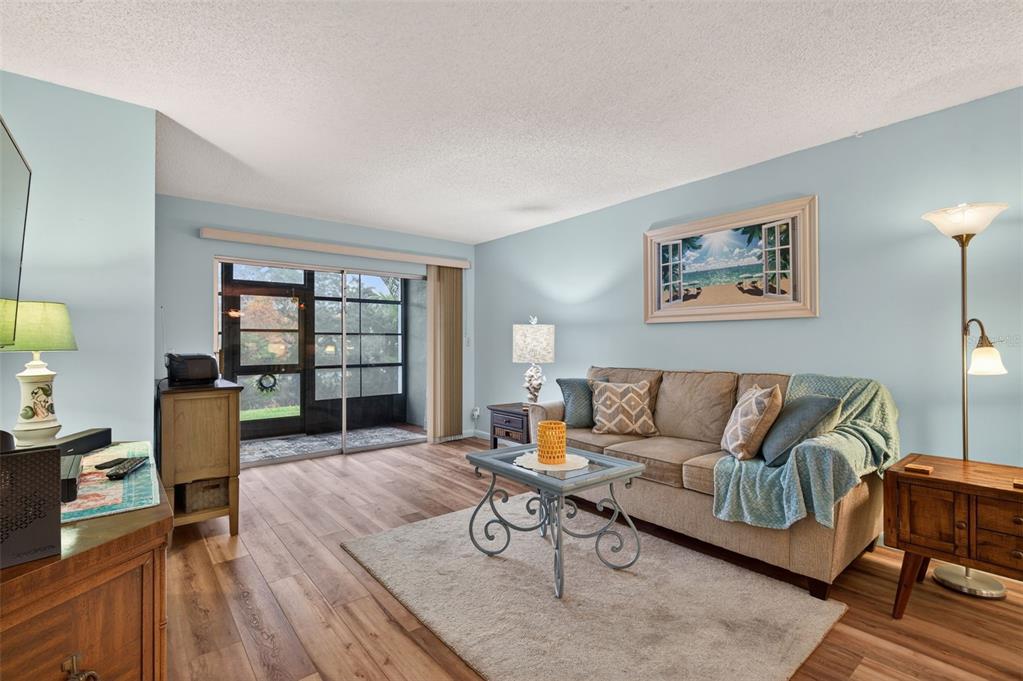 1430 Heather Ridge Boulevard, Unit 101 Dunedin, FL 34698 - Photo 8 of 44 a living room with furniture and a flat screen tv with wooden floor