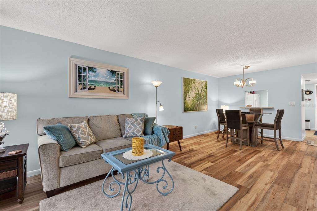 1430 Heather Ridge Boulevard, Unit 101 Dunedin, FL 34698 - Photo 9 of 44 a living room with furniture and a dining table with wooden floor