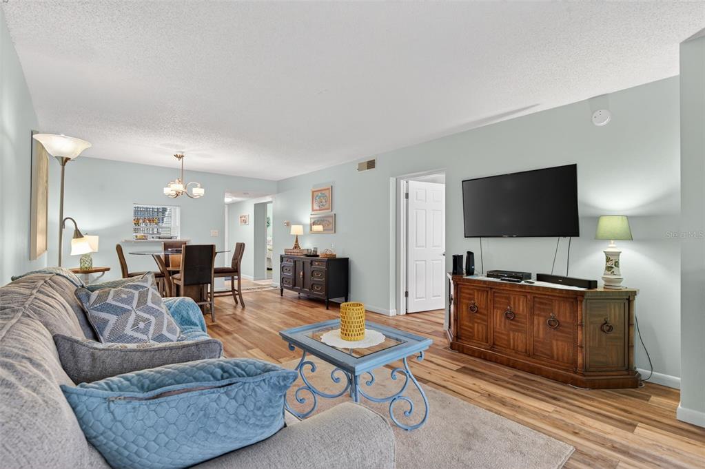 1430 Heather Ridge Boulevard, Unit 101 Dunedin, FL 34698 - Photo 10 of 44 a living room with furniture a flat screen tv and kitchen view