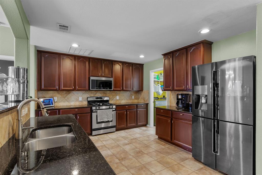 3213 Evening Wind Road Denton, TX 76208 - Photo 10 of 28 a kitchen with granite countertop stainless steel appliances a refrigerator stove top oven a sink and dishwasher