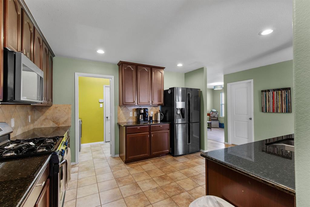 3213 Evening Wind Road Denton, TX 76208 - Photo 11 of 28 a kitchen with stainless steel appliances granite countertop a stove refrigerator and a sink