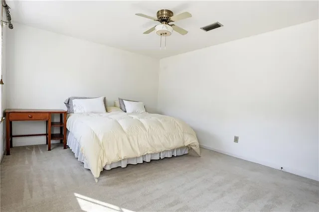 a spacious bedroom with a bed and a chandelier fan