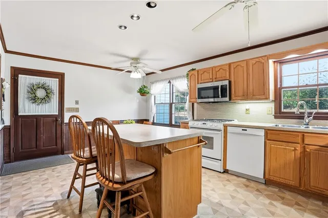 a open kitchen with stainless steel appliances granite countertop a stove top oven a sink dishwasher a dining table and chairs with wooden floor