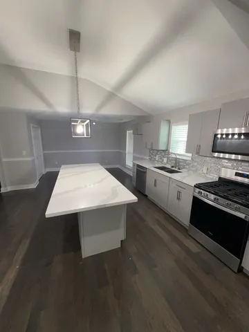 a kitchen with a stove a sink and wooden floor