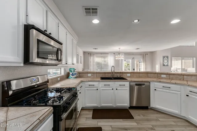 a kitchen with stainless steel appliances granite countertop a stove a sink and a microwave