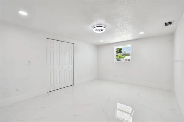 an empty room with windows and fan