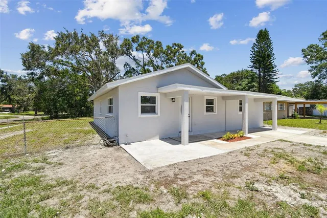a front view of a house with a yard outdoor seating and covered with trees