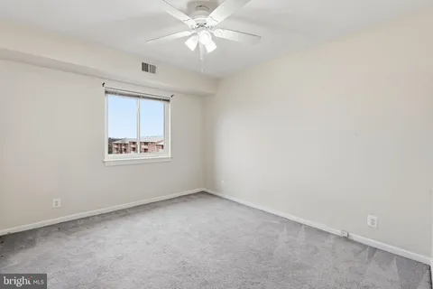 an empty room with a window and a fan