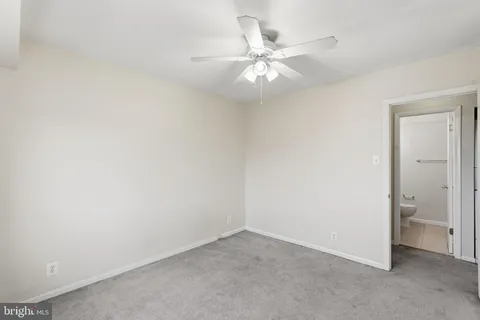 an empty room with a fan and a bathroom