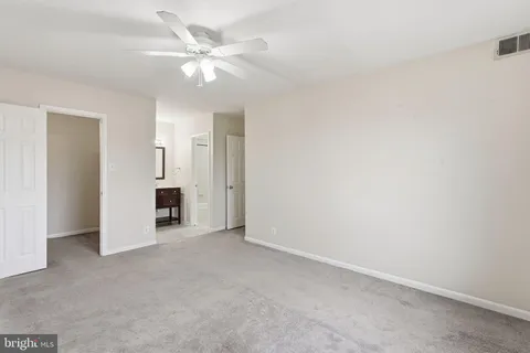an empty room with closet and a ceiling fan
