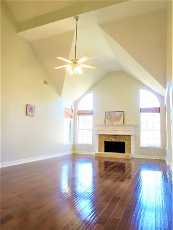 a view of an empty room with window and wooden floor