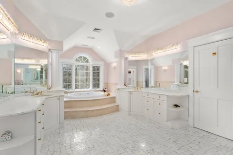 a large white bathroom with a granite countertop double vanity sink a bathtub and window