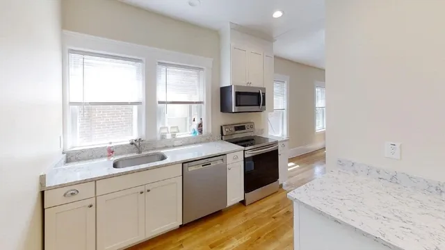 a kitchen with granite countertop a sink and a stove top oven with wooden floor