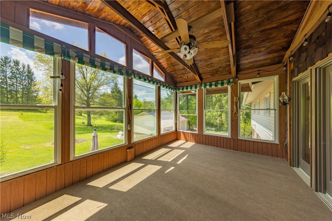 7969 Dines Road Novelty, OH 44072 - Photo 16 of 48 Sunroom featuring abundant natural light from numerous windows, a wood-paneled vaulted ceiling, exposed wood beams, ceiling fan, and carpeted flooring