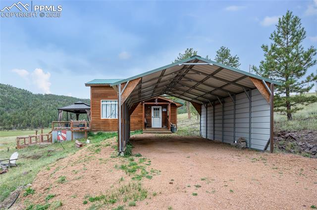 608 Slater Creek Road Guffey, CO 80820 - Photo 8 of 47 View of parking featuring a carport, a view of trees, and dirt driveway