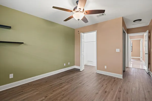an empty room with wooden floor and a ceiling fan