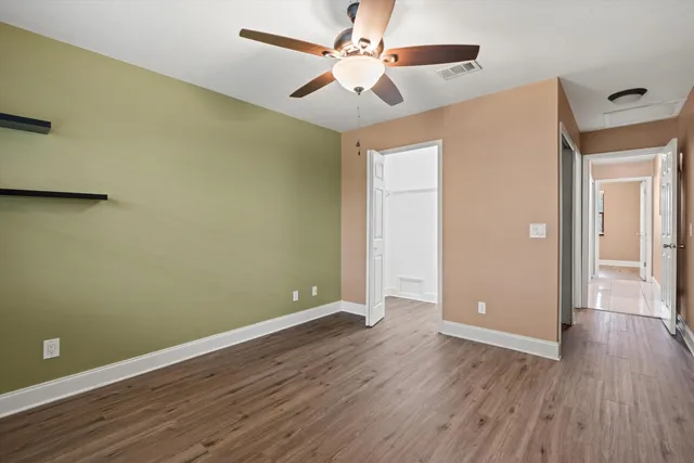 an empty room with wooden floor and a ceiling fan
