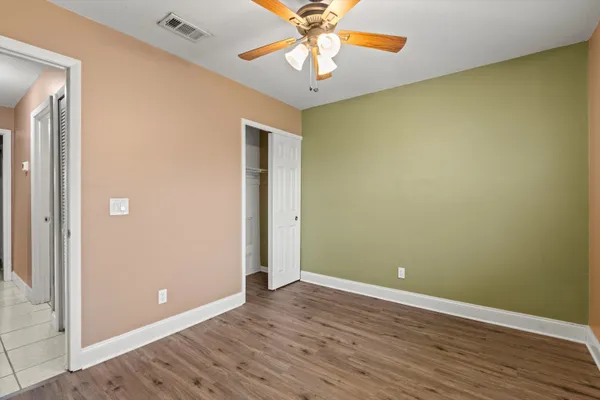 an empty room with wooden floor and a chandelier fan