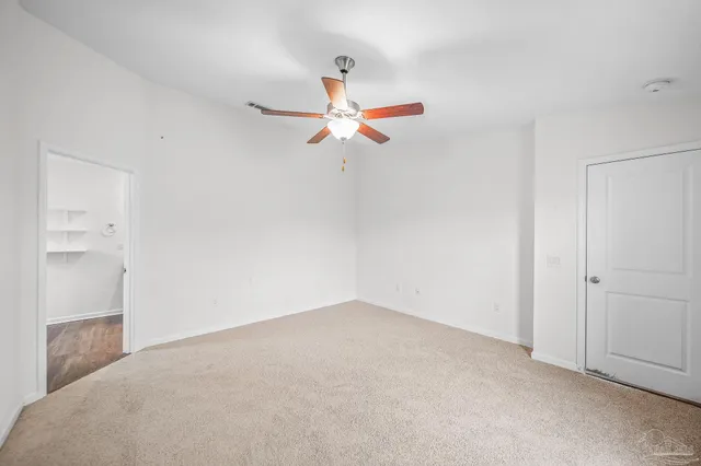 an empty room with windows and fan
