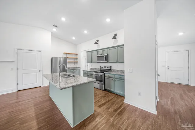 a kitchen with stainless steel appliances granite countertop a refrigerator oven a sink dishwasher and white cabinets with wooden floor