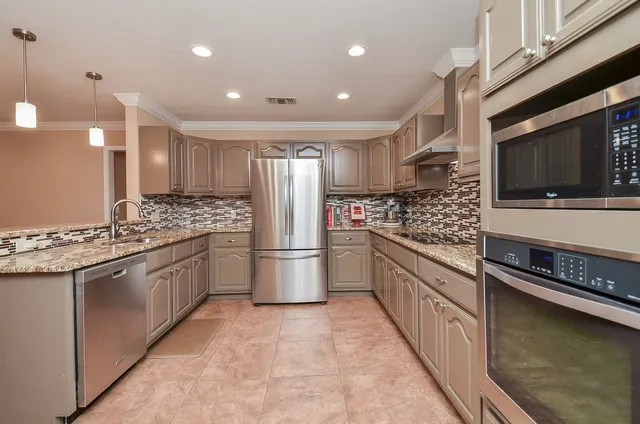 a kitchen with stainless steel appliances kitchen island granite countertop a refrigerator and stove