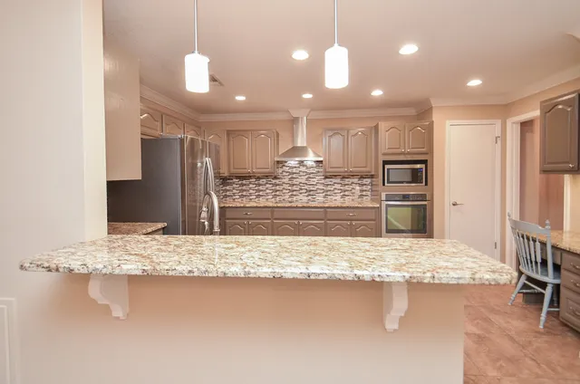 a kitchen with stainless steel appliances granite countertop a refrigerator a sink a stove and a wooden floors