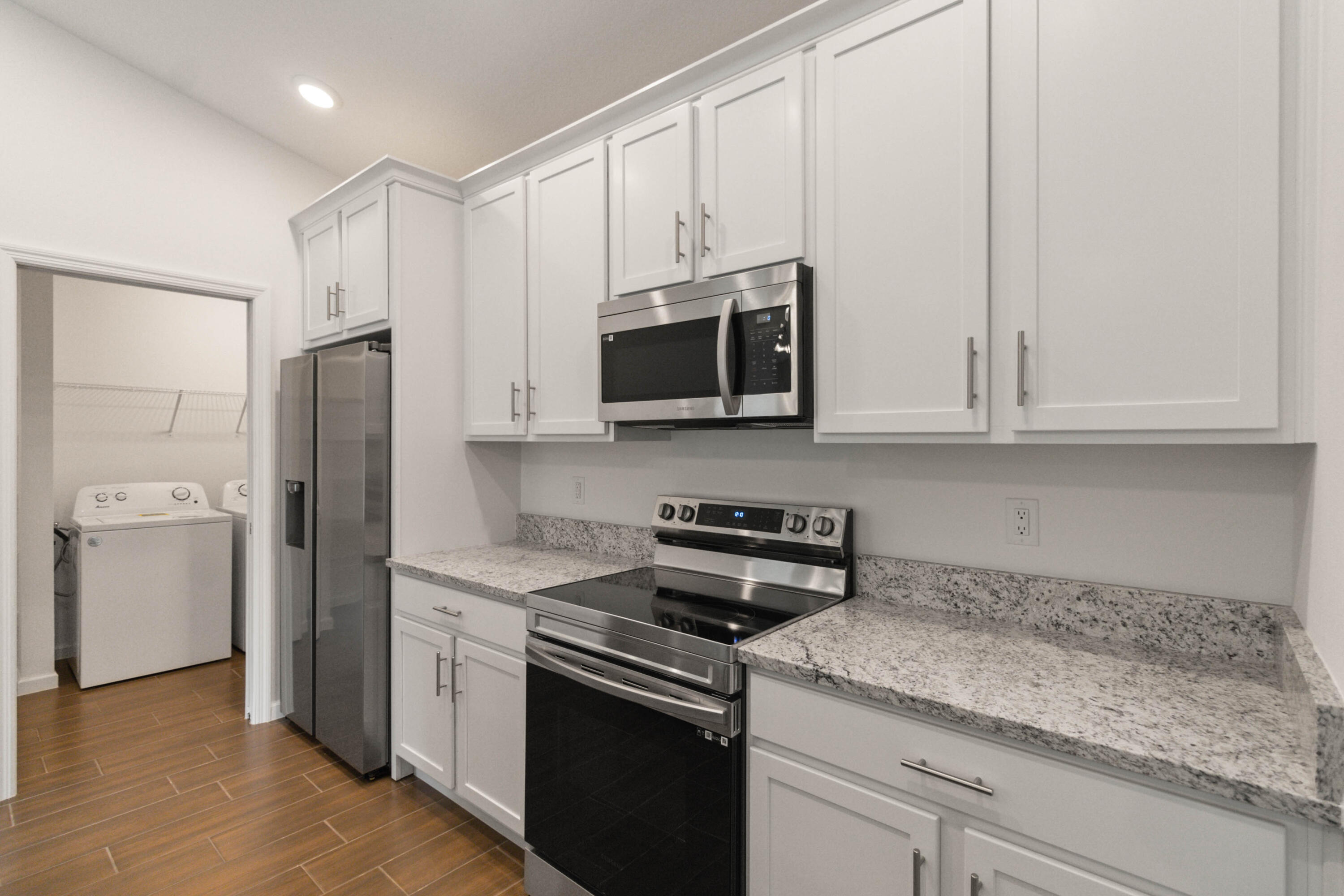 336 Rheine Road Northwest Palm Bay, FL 32907 - Photo 5 of 30 a kitchen with stainless steel appliances granite countertop white cabinets and a stove a refrigerator with wooden floor