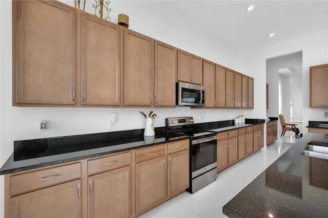 a kitchen with stainless steel appliances a dining table chairs refrigerator and microwave