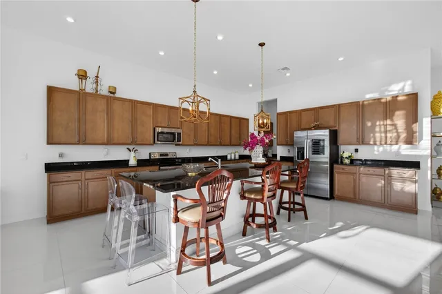 a kitchen with granite countertop a refrigerator a sink a stove and chairs