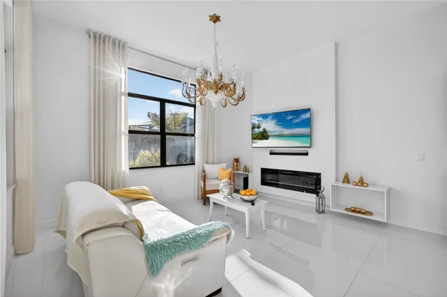 a living room with furniture kitchen view and a chandelier