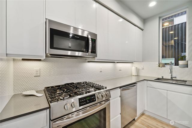 a kitchen with stainless steel appliances a sink a stove and microwave