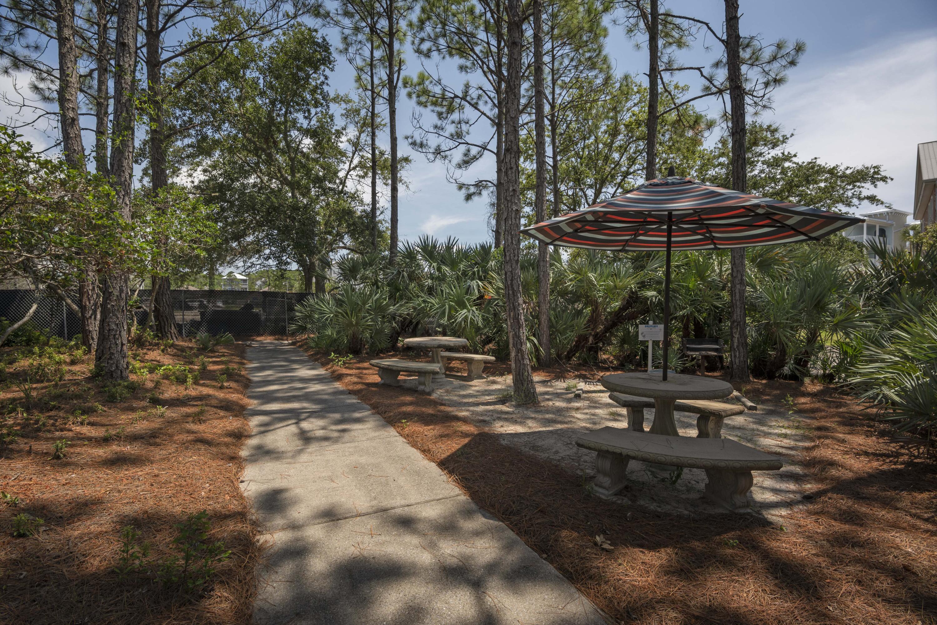 1740 South County Highway, Unit 203 Santa Rosa Beach, FL 32459 - Photo 29 of 40 a view of a backyard with table and chairs under an umbrella