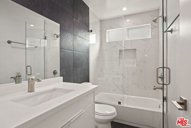 a bathroom with a bathtub shower sink vanity and toilet