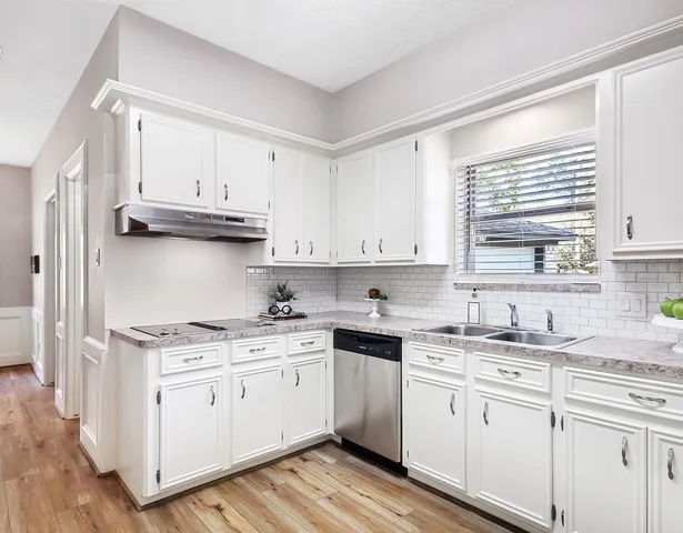 a kitchen with cabinets appliances a sink and a window